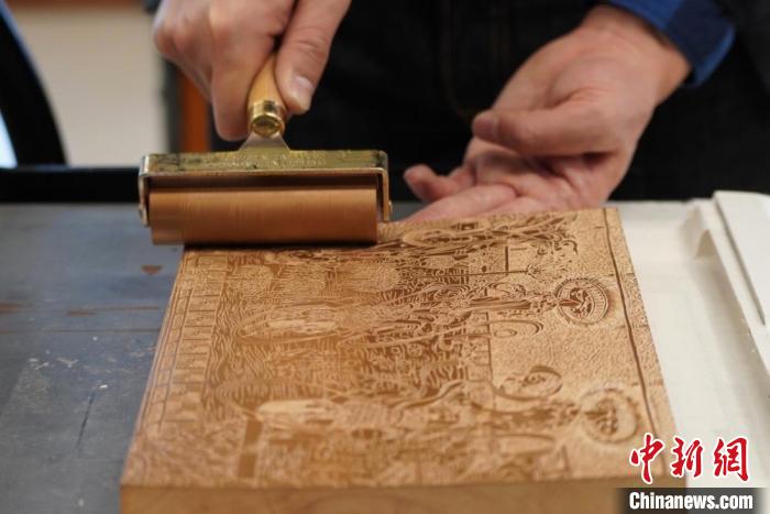 圖為徐晉林工作室工作人員正在給雕好壁畫的版面滾油墨?！【琶赖┰?　攝