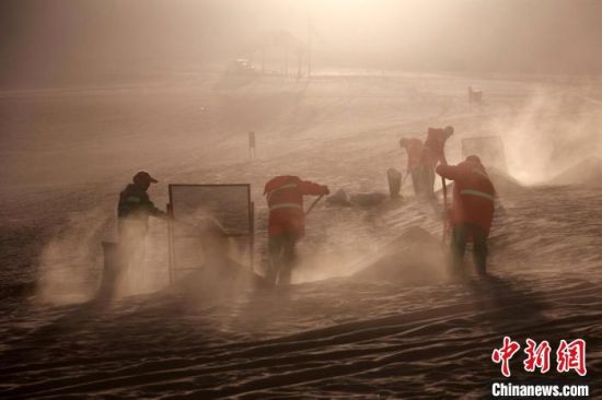 圖為敦煌市鳴沙山月牙泉景區(qū)“駱駝保姆”清理駱駝糞便?！垥粤?攝