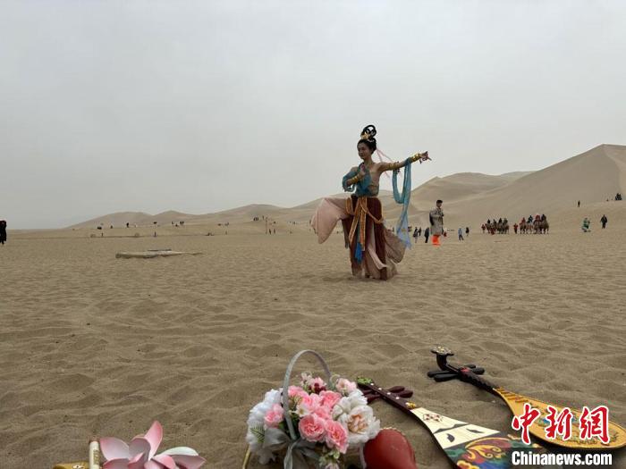 圖為2023年4月底，敦煌大漠“逐舞者”奧楠在鳴沙山月牙泉景區(qū)視頻直播敦煌舞。　馮志軍 攝