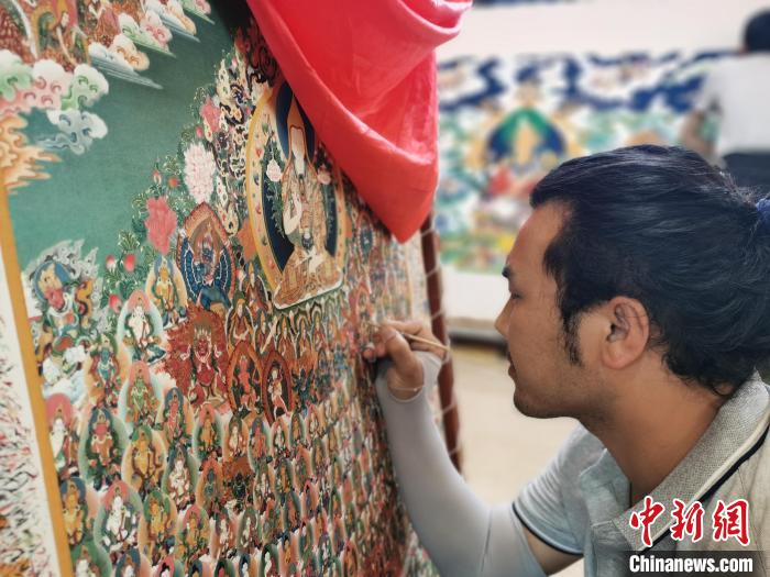 圖為更登才讓的徒弟繪畫唐卡?！?zhí)砀?攝