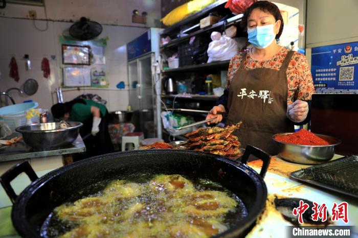 圖為平安驛·河湟民俗文化體驗地內(nèi)的商戶炸干板魚?！⊙Φ?攝